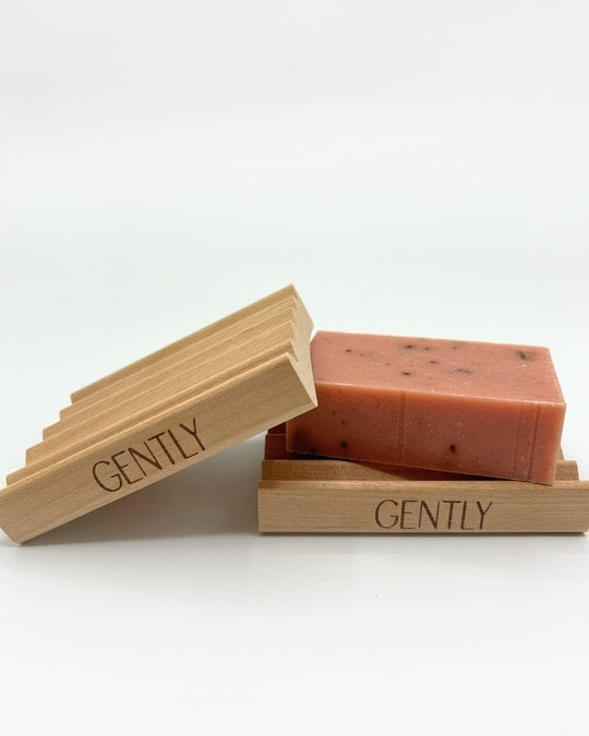 Two wooden Gently Soap Trays laying diagonally with one with a pink bar soap on top.